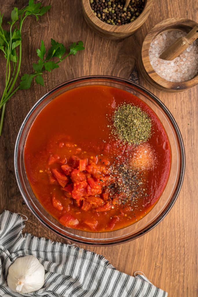 Mixing bowl filled with tomato sauce, diced tomatoes, and seasonings ready to be whisked together for the Cabbage Rolls sauce.