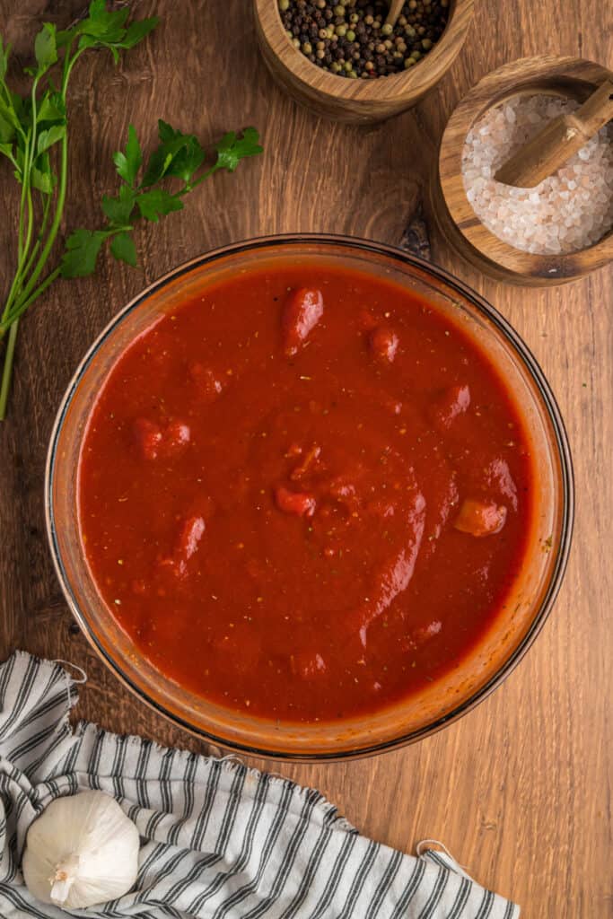 Prepared tomato sauce mixture in a glass bowl, showing blended diced tomatoes, tomato sauce, and seasonings.