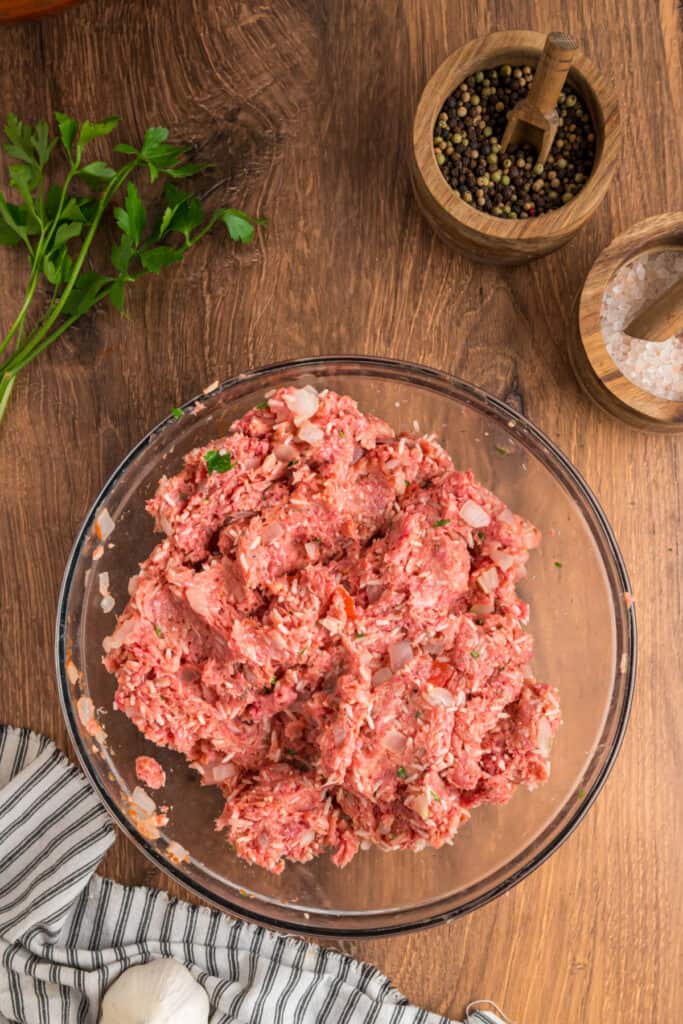 Meat mixture for the Cabbage Rolls fully mixed with rice, onions, and parsley in a glass bowl.