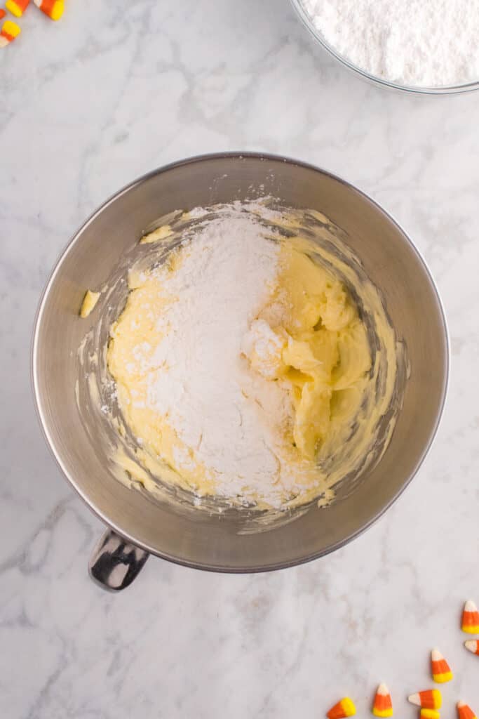 Butter being creamed with powdered sugar in a mixing bowl to make frosting.