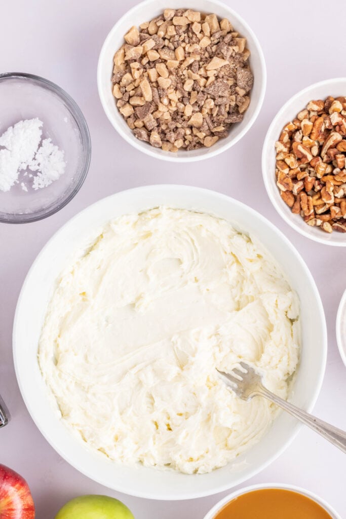 Cream cheese mixture smoothed in a white bowl with a fork, ready for layering.