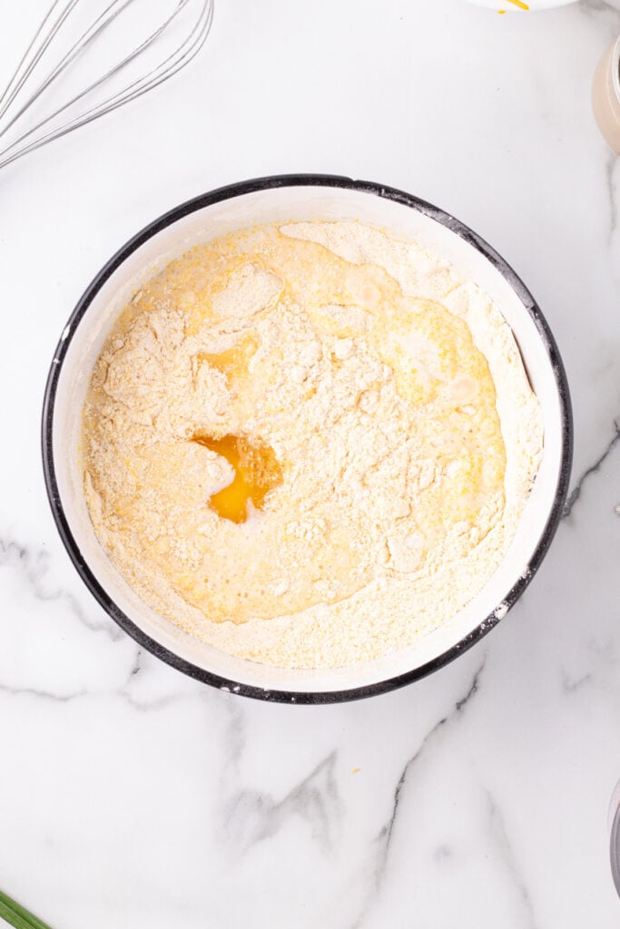 Dry ingredients for Cheddar Onion Cornbread with milk and egg added to the center before mixing.