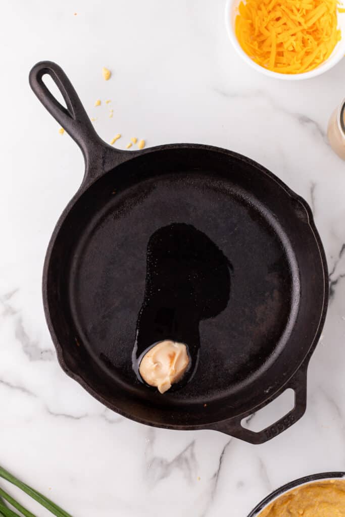 Cast iron skillet with melted bacon grease heating before adding Cheddar Onion Cornbread batter.