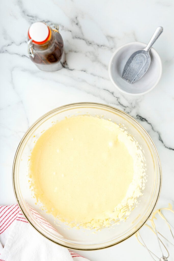 Fluffy egg yolk and sugar mixture in a glass mixing bowl after beating.