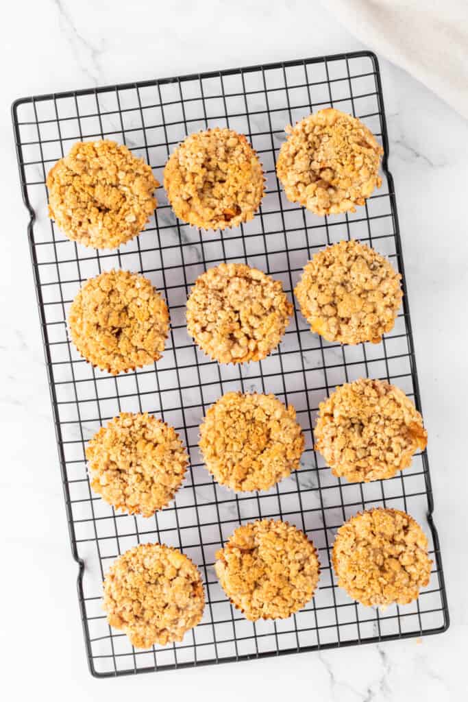 Freshly baked Mini Apple Crumble Cheesecakes cooling on a wire rack, golden and crisp on top.
