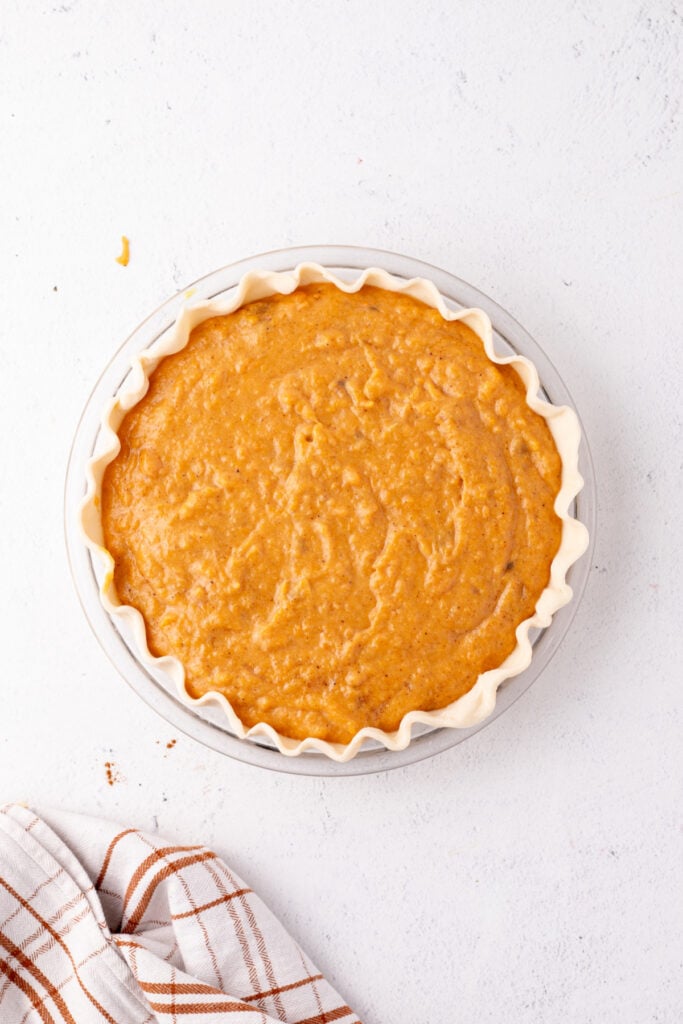 Unbaked sweet potato pie filled with smooth orange filling, ready to go into the oven.