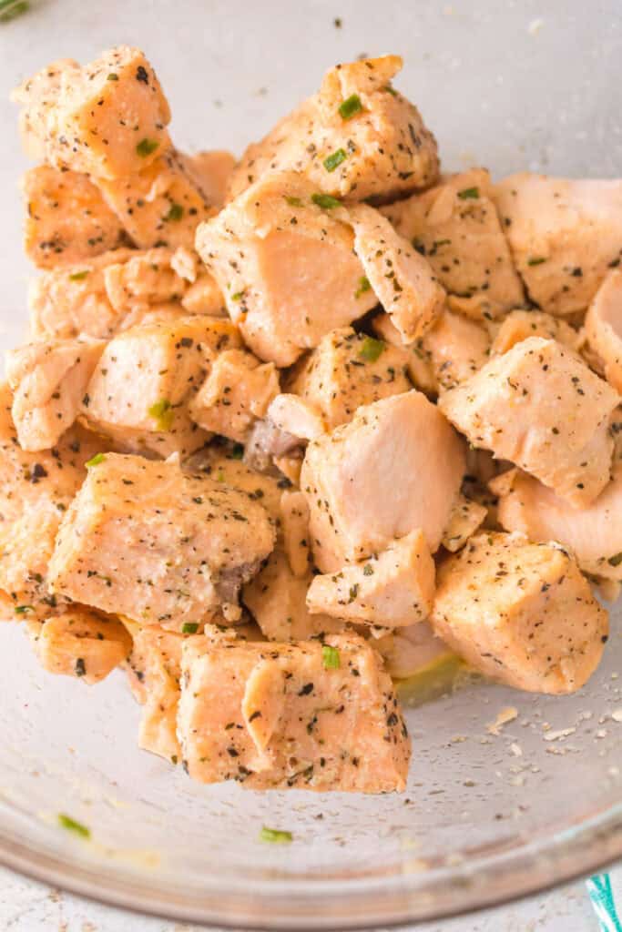 Close-up of salmon bites coated in garlic butter and herbs, showing tender flaky texture.