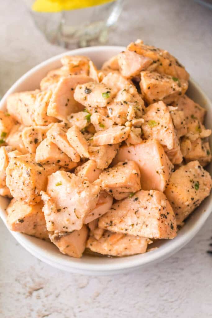 Overhead shot of a bowl of air fryer salmon bites garnished with herbs, ready to serve.