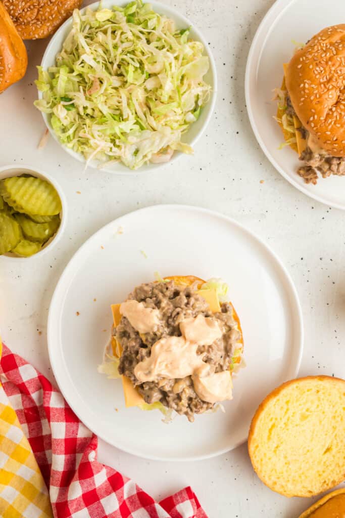 Adding creamy Big Mac sauce over the beef mixture while assembling the sandwich.