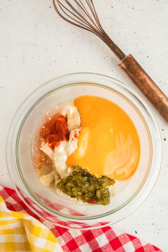 Mixing bowl filled with Big Mac sauce ingredients, including mayonnaise, relish, french dressing, and seasonings before whisking.