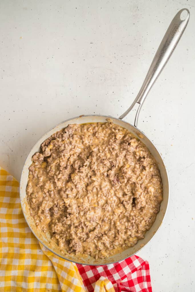 Finished cheesy Big Mac Sloppy Joes beef mixture simmering in a skillet on a white background.