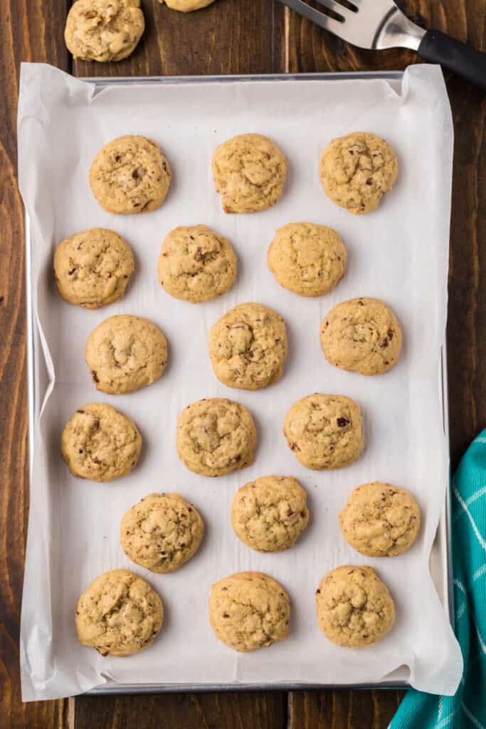 Freshly baked Butter Pecan Cookies cooling on a parchment-lined baking sheet with golden edges.