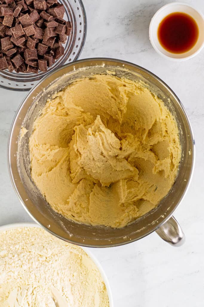 Creamed butter and sugars in a mixing bowl, smooth and fluffy, with ingredients surrounding the bowl.