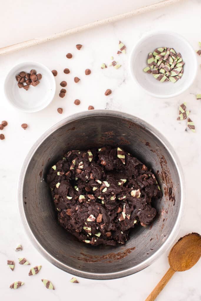 Fully mixed chocolate mint cookie dough with mint and chocolate chips evenly distributed in a large bowl.