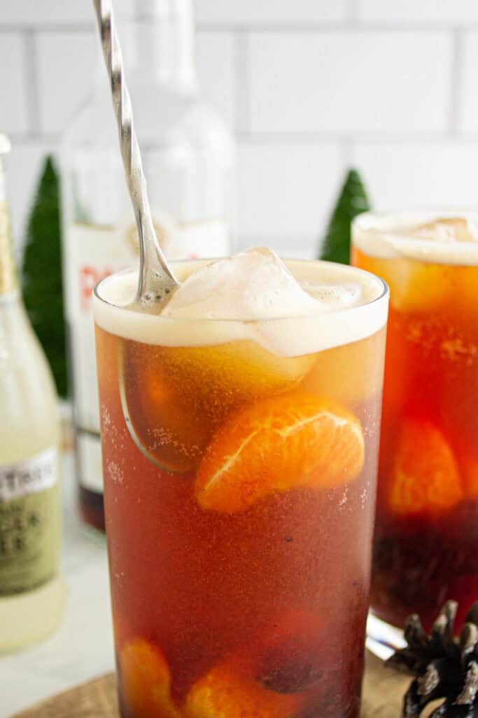 Stirring the Cranberry Pimm’s Cocktail with a bar spoon to blend the ingredients.