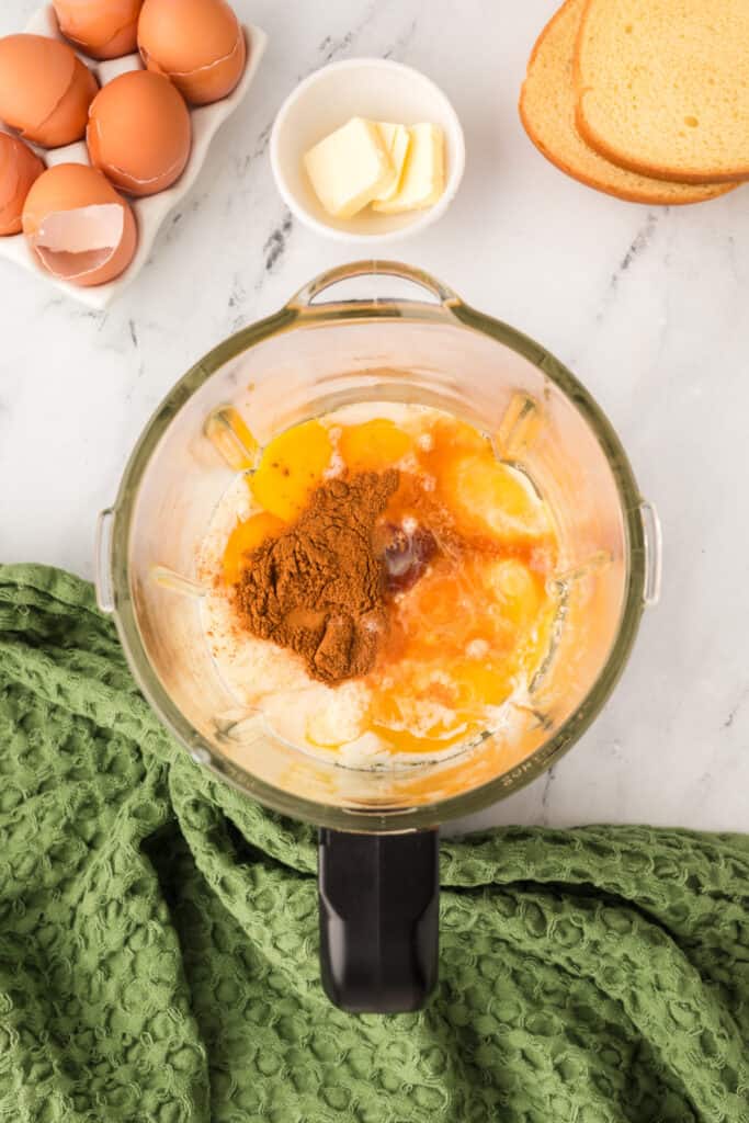 Blender filled with eggs, cinnamon, and vanilla ready to blend for Eggnog French Toast mixture.