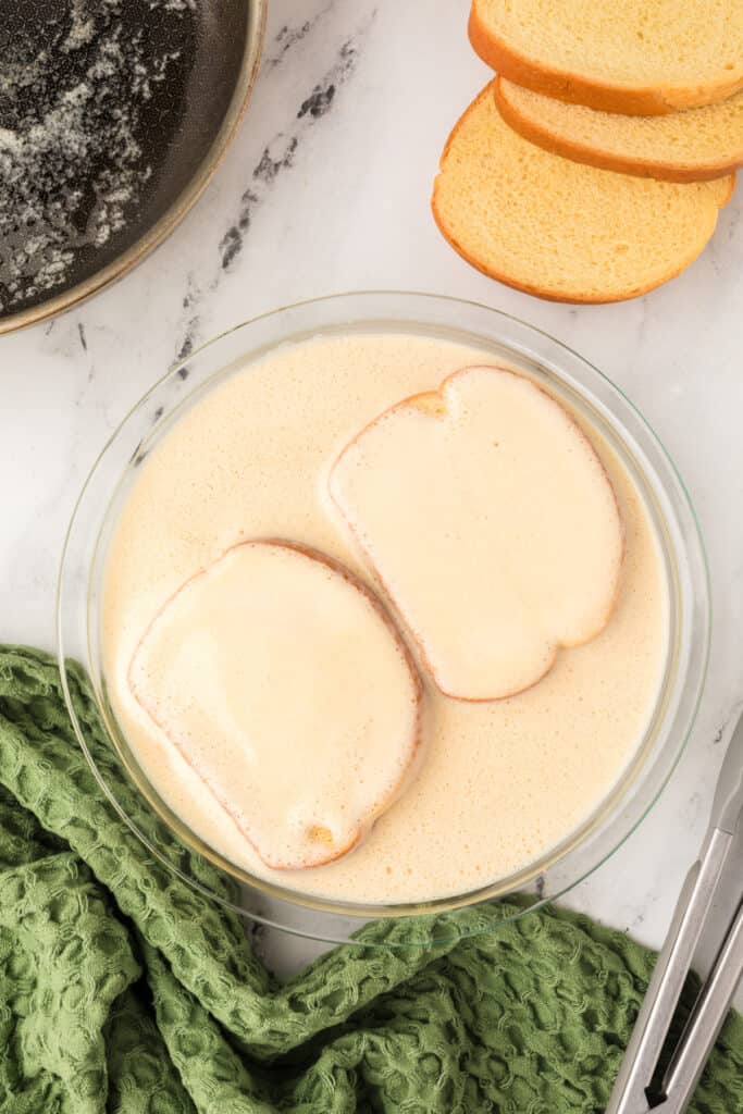 Bread slices coated in eggnog custard, fully soaked and ready to cook.