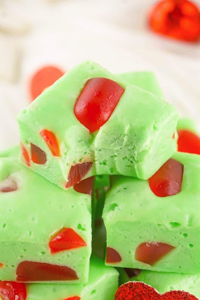 A stack of green Grinch Christmas Nougat cubes with red gumdrop pieces and a bite taken from the top piece.