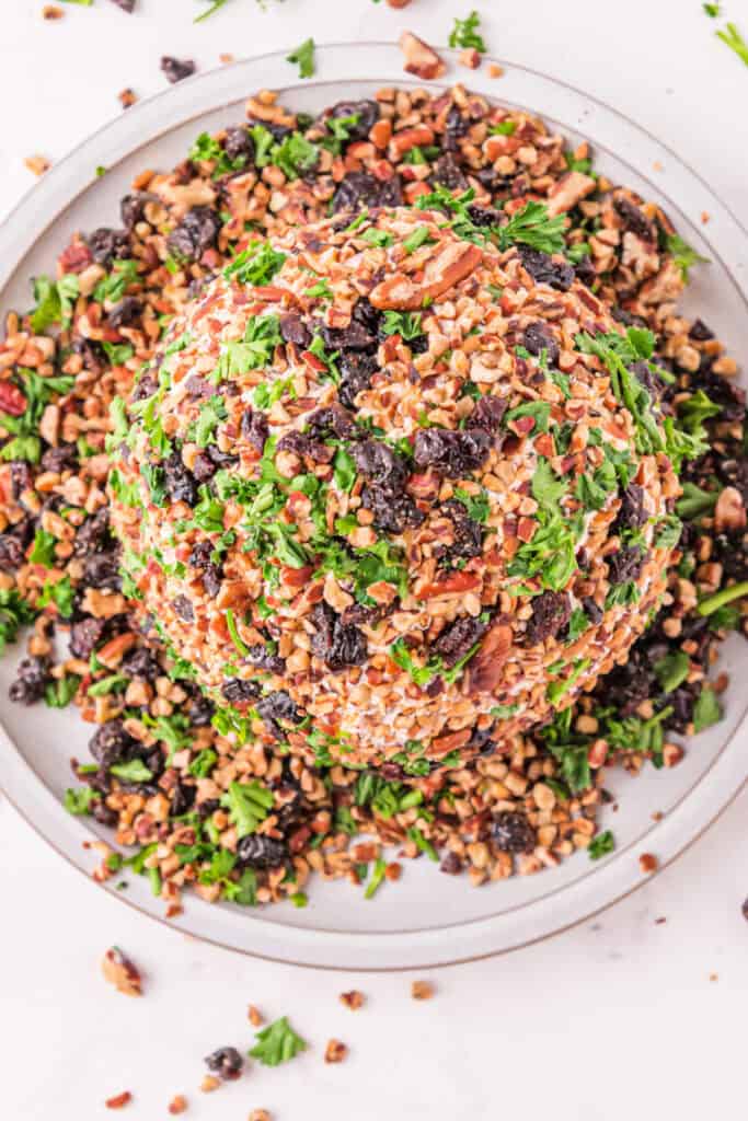 Holiday Cheese Ball fully coated with chopped pecans, dried cherries, and parsley for a festive look.