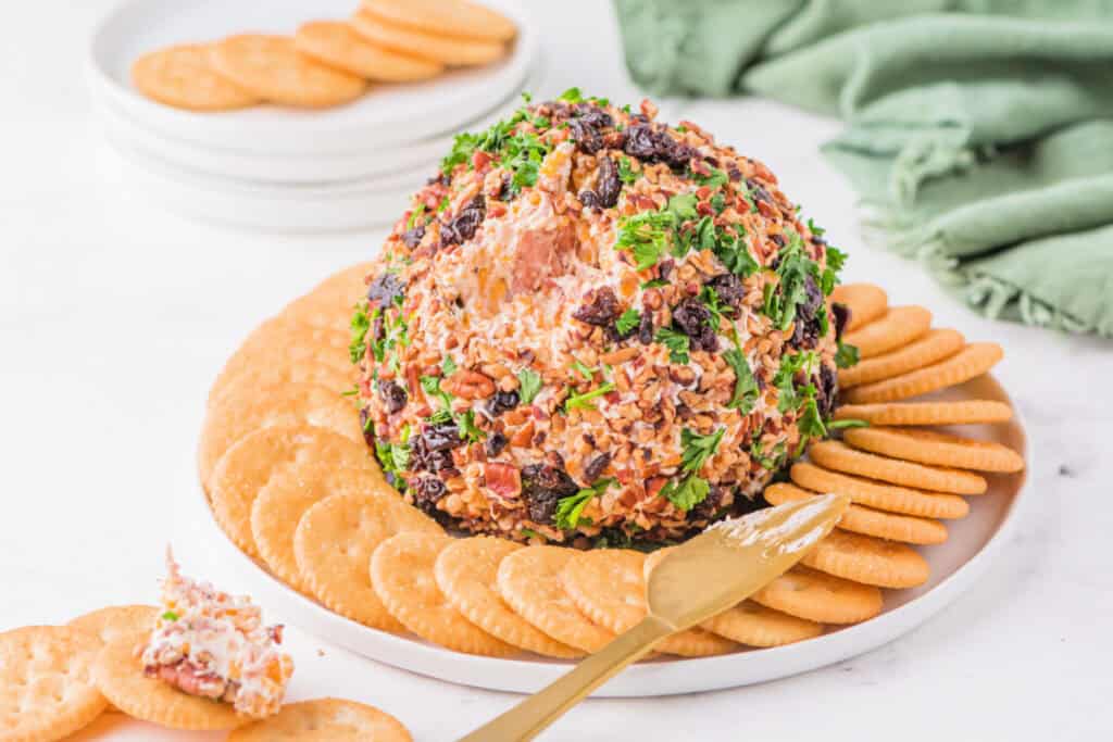 Holiday Cheese Ball on a white plate with green napkin in the background, showing texture and serving setup.