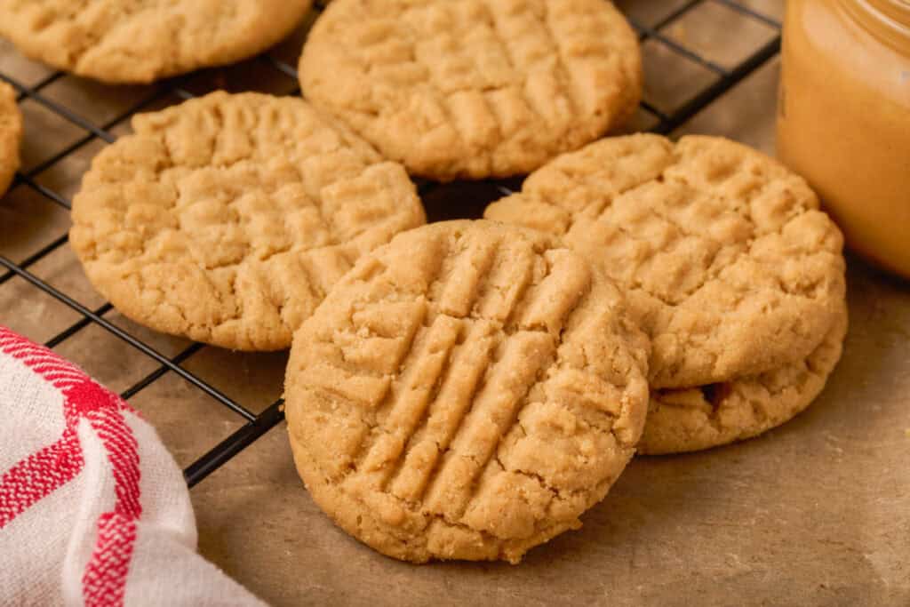 Close-up of golden brown peanut butter cookies on a wire rack showing detailed crisscross patterns.