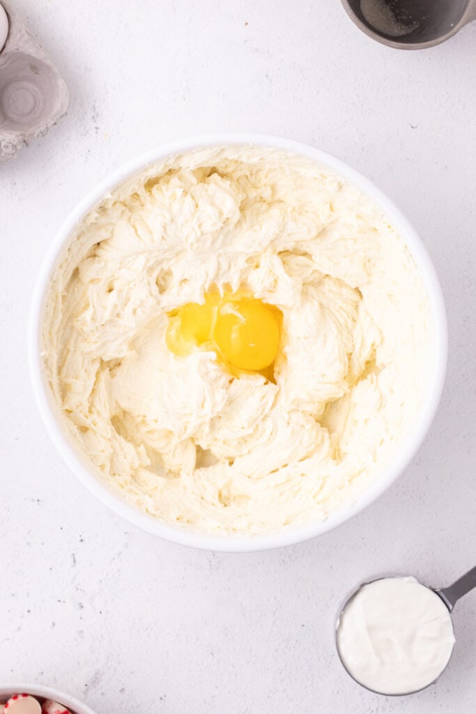 Egg yolks added to the beaten cream cheese mixture in preparation for blending into the cheesecake batter.