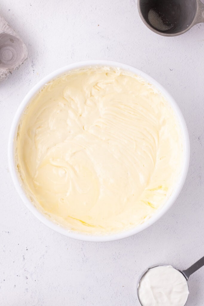 Smooth cheesecake batter in a mixing bowl after adding eggs and blending until creamy.