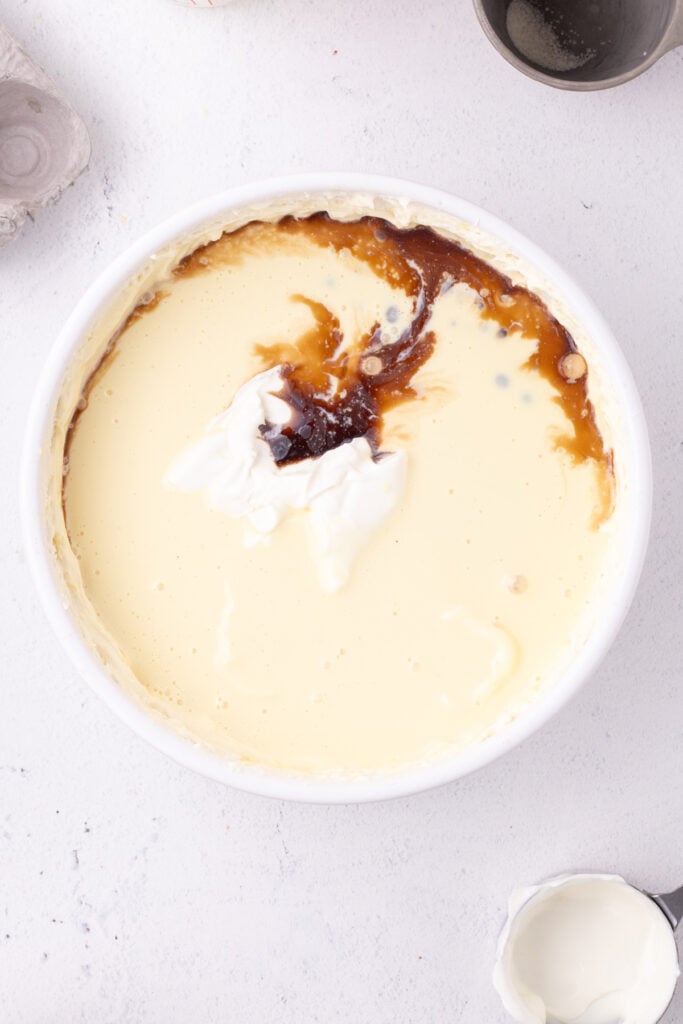 Cheesecake batter with eggnog, sour cream, and vanilla extract added but not yet mixed in.