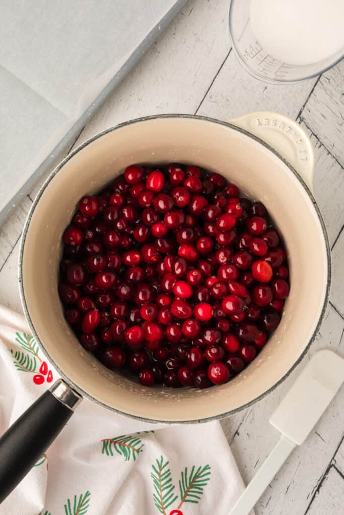 Fresh cranberries added to the saucepan of sugar syrup, ready to be coated for sugared cranberries.