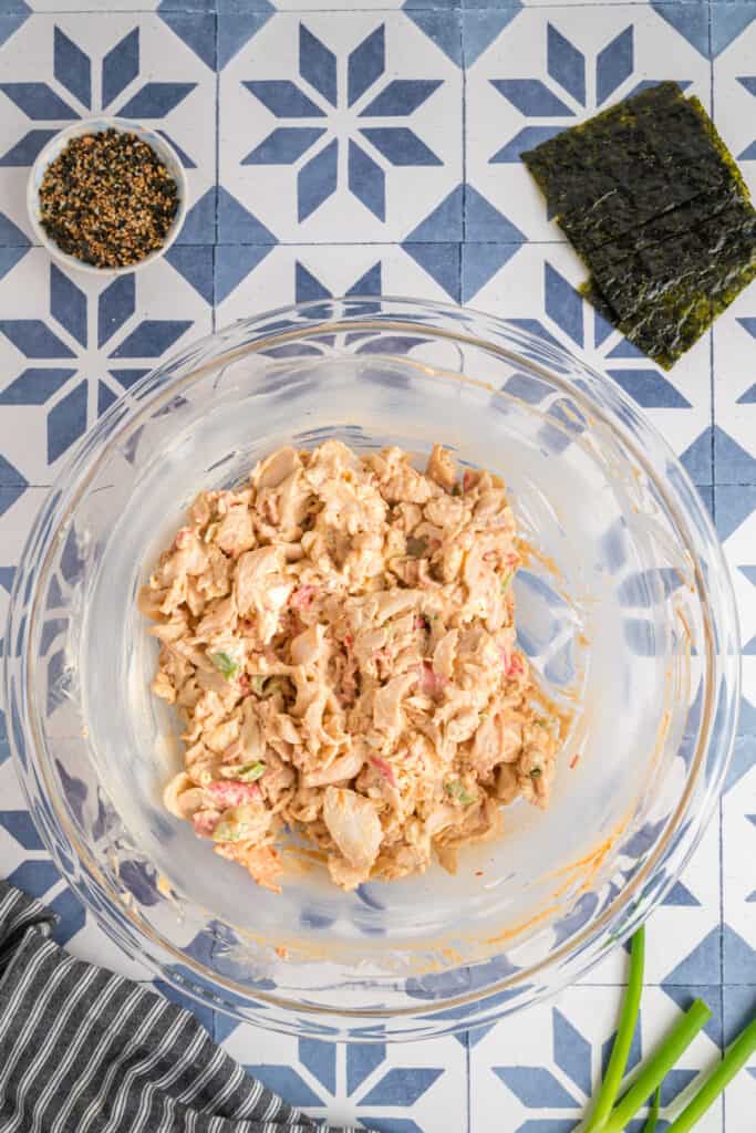 Sushi bake mixture fully combined in a glass bowl, showing creamy crab and sriracha filling ready to layer over rice.