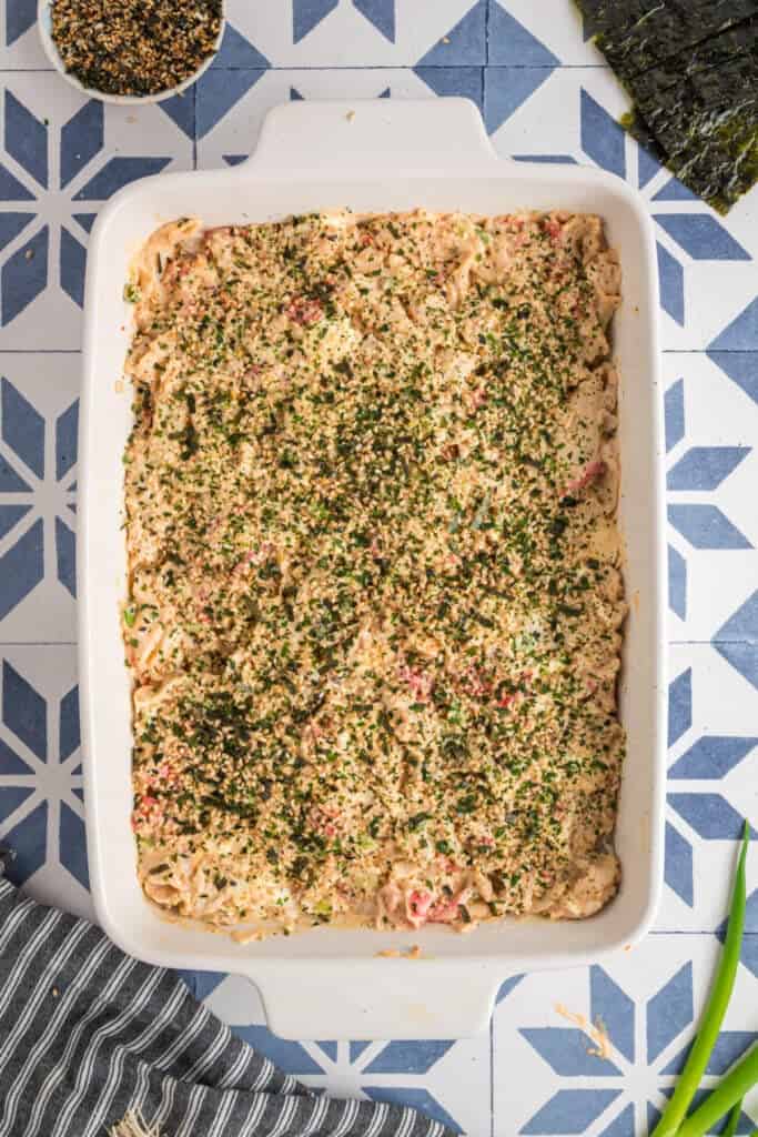 Sushi bake topped generously with furikake seasoning, adding color and texture before baking.