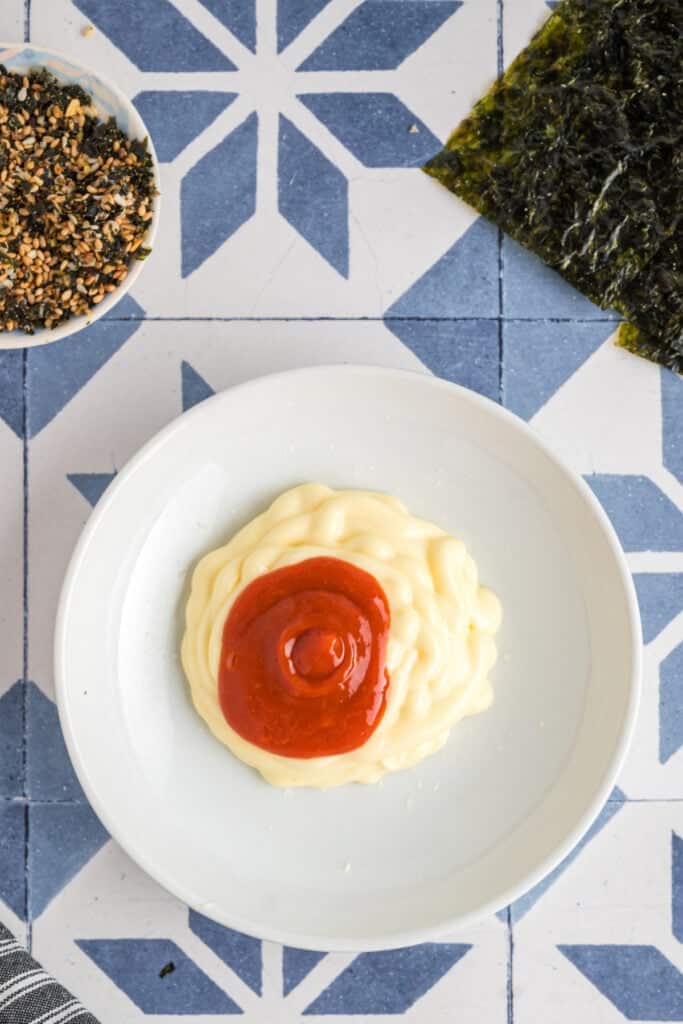 Small dish of mayonnaise and sriracha sauce side by side, ready to be mixed into a spicy topping.
