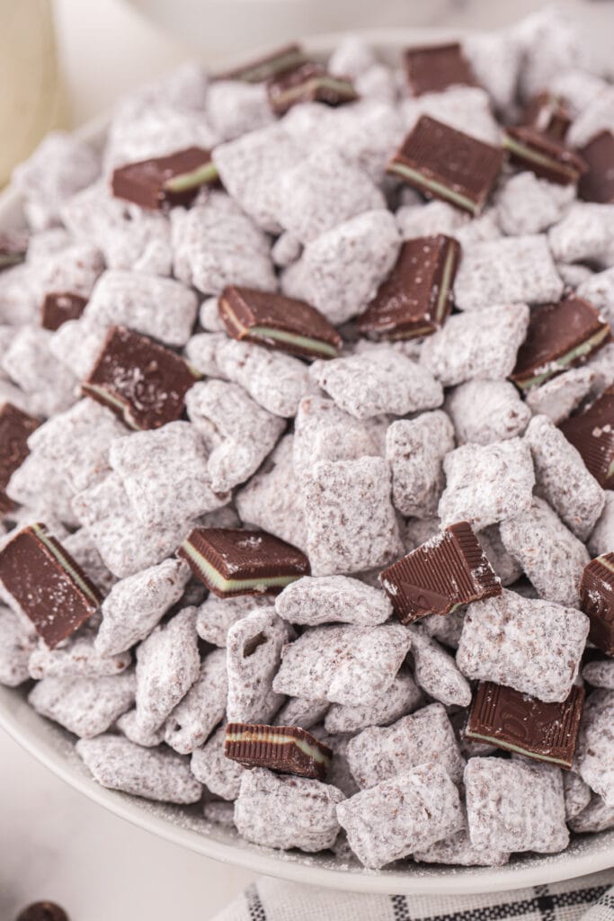 Close up of Thin Mint Muddy Buddies showing the powdered sugar coating and pieces of Andes mints mixed throughout.