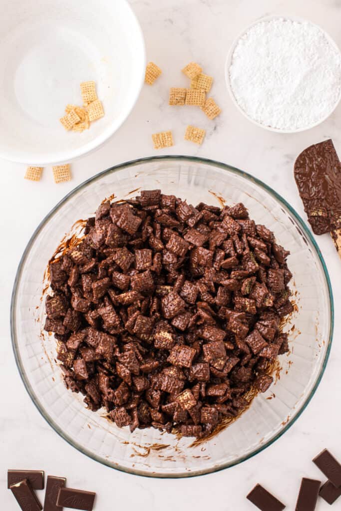 Rice Chex cereal fully coated in melted chocolate inside a large mixing bowl.