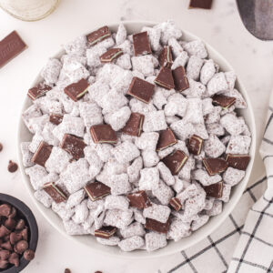 Overhead square shot of a full bowl of Thin Mint Muddy Buddies with chopped Andes mints scattered on top.