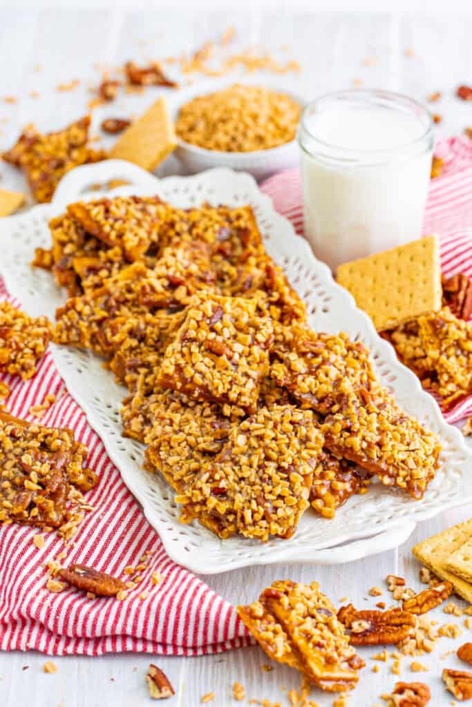 platter of toffee graham cracker pralines arranged with a glass of milk and scattered graham crackers