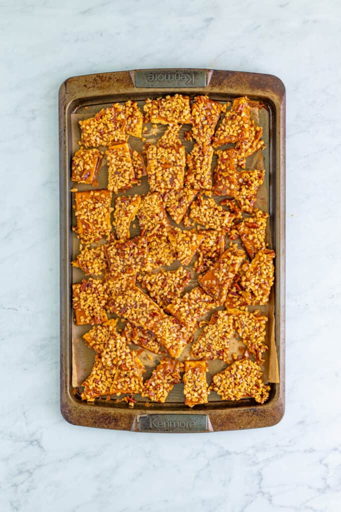 cooled sheet of toffee graham cracker pralines broken into individual pieces on a baking sheet