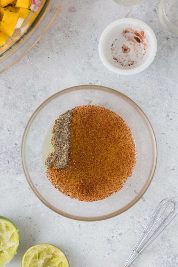 Seasoning mixture of pepper and chili powder added to lime juice in a small bowl.