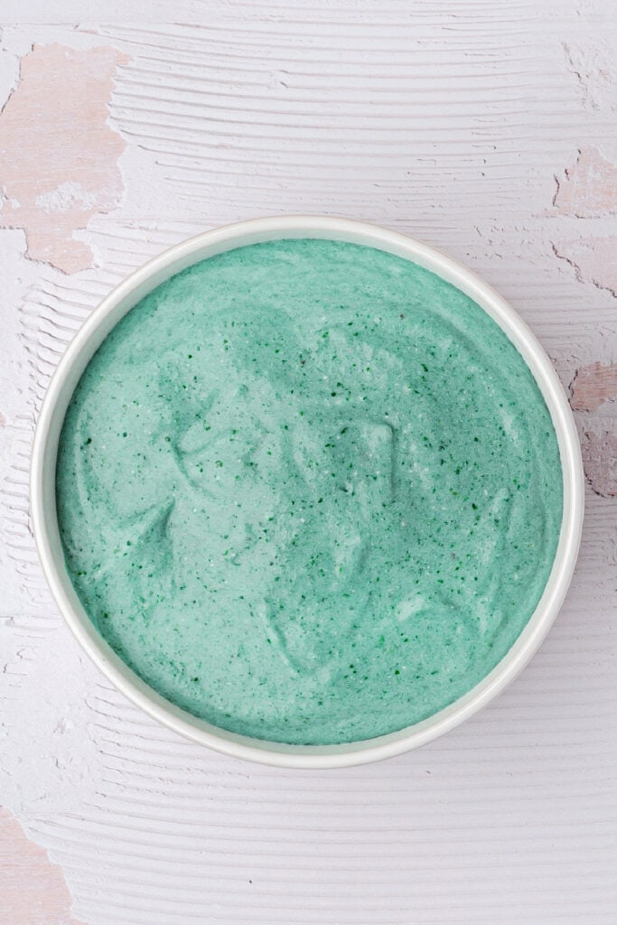 Overhead view of a smooth blue spirulina smoothie bowl in a white bowl with a clean, minimalist background.