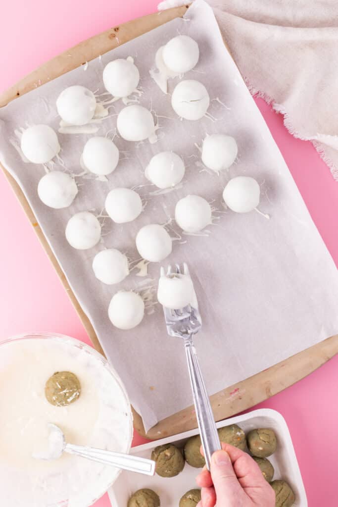 Cake truffle balls dipped in melted white chocolate on parchment paper