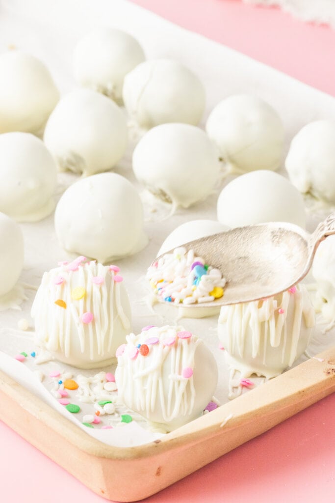 Decorating white chocolate cake truffles with colorful sprinkles