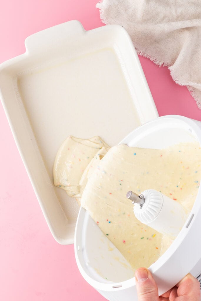 Baked funfetti cake being removed from a pan after cooling