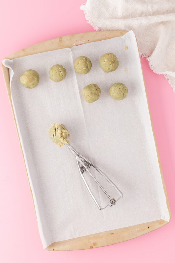 Cake truffle mixture rolled into balls on a parchment-lined baking sheet