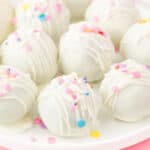 Close-up of white chocolate birthday cake truffles with drizzle and pastel sprinkles on a plate