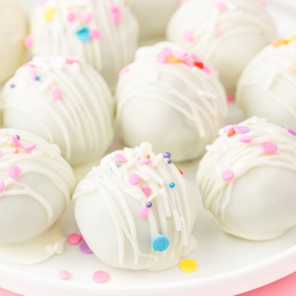 Close-up of white chocolate birthday cake truffles with drizzle and pastel sprinkles on a plate