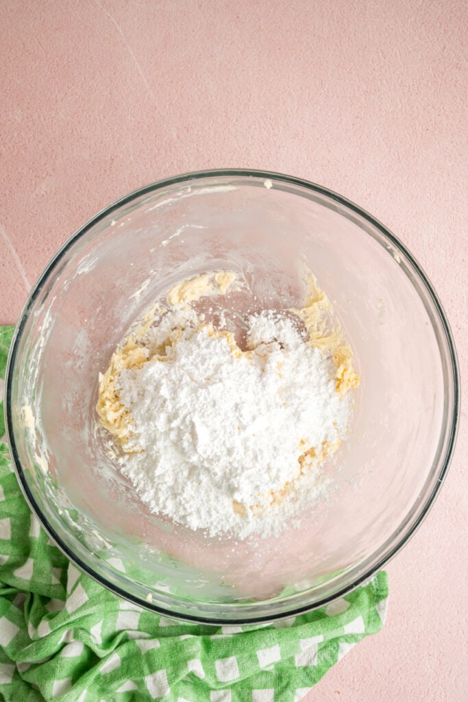 powdered sugar added to the butter mixture in a glass mixing bowl