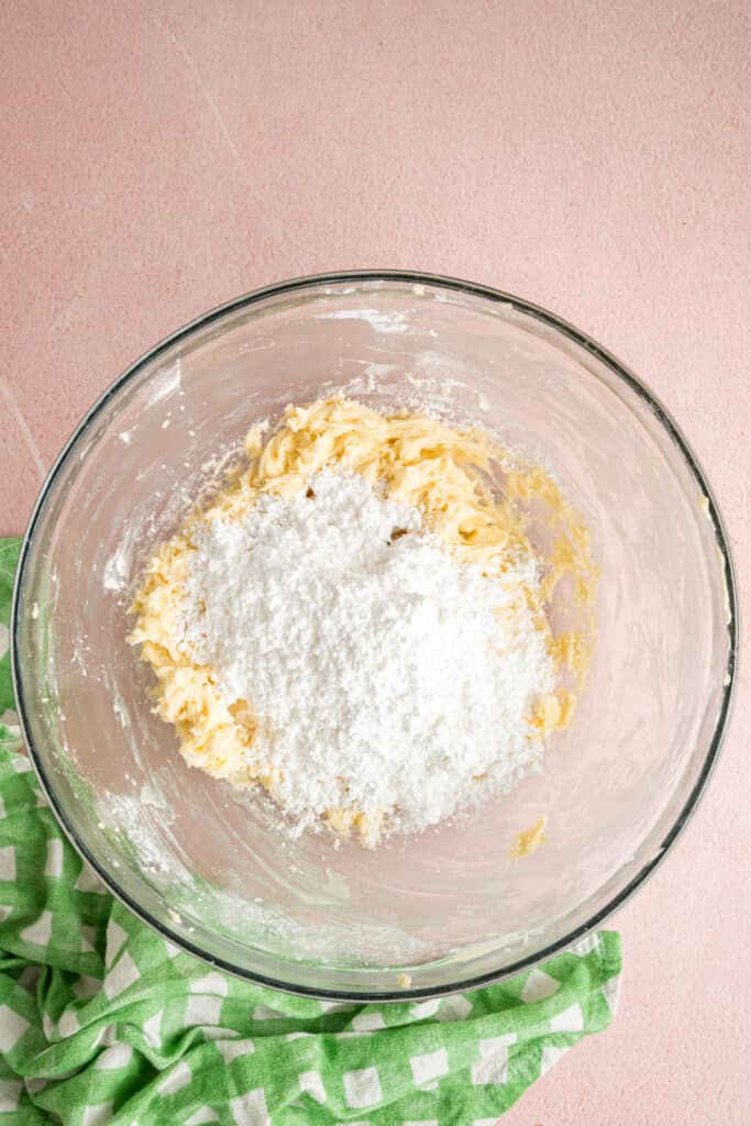 additional powdered sugar added to the butter mixture in a glass mixing bowl