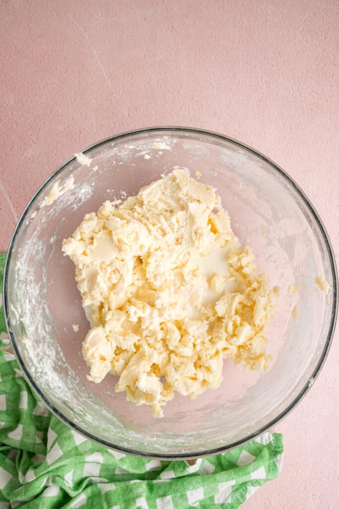 thick buttercream mixture with milk added to the top forming in a glass mixing bowl