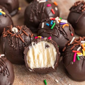buttercream truffles on wooden surface with front one cut in half to show the inside
