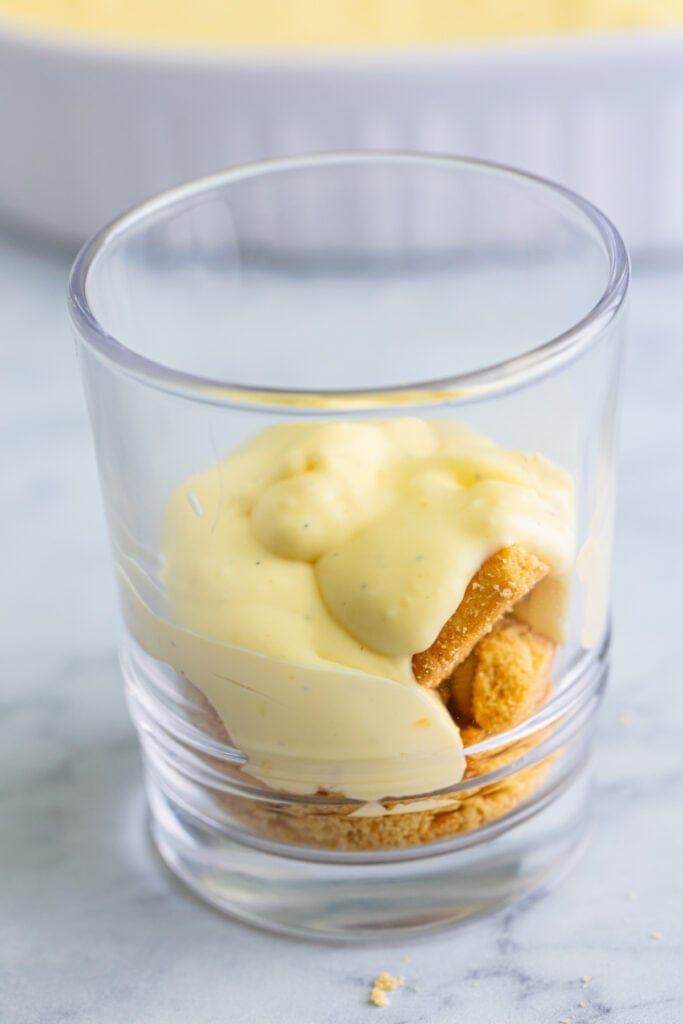 vanilla custard spooned over shortbread cookies in a clear trifle glass